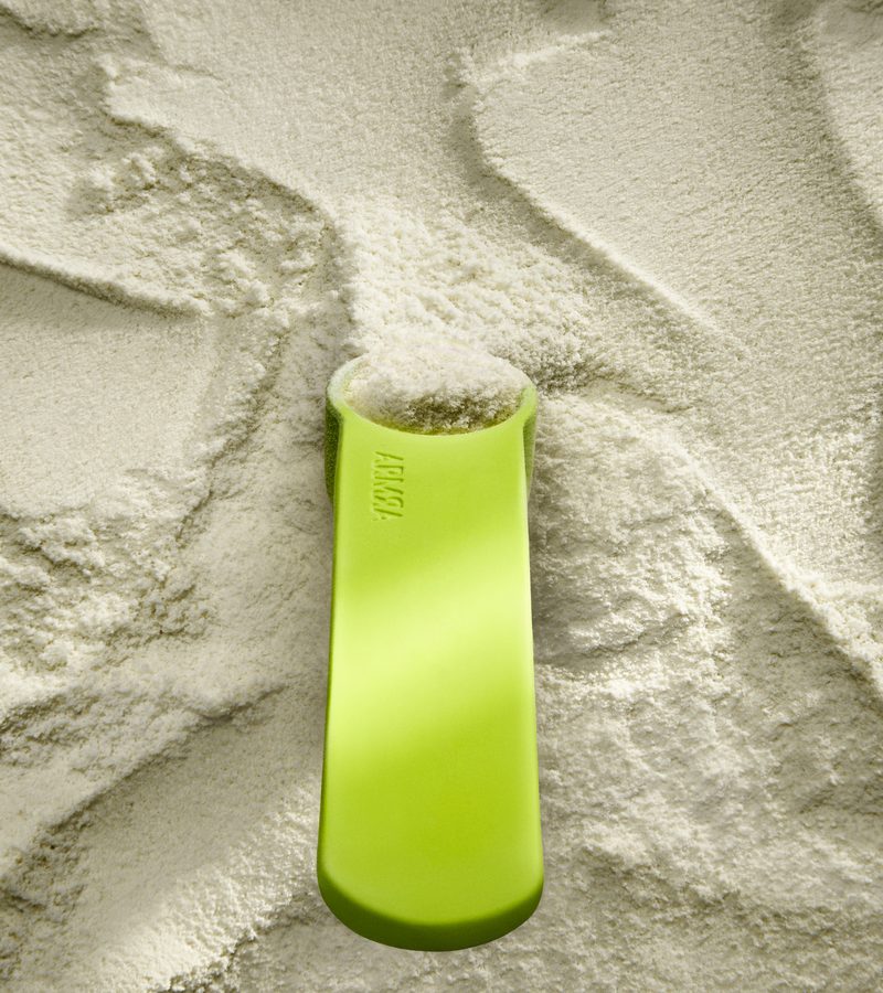 ARMRA Colostrum powder close-up with the brand&rsquo;s neon measuring scoop